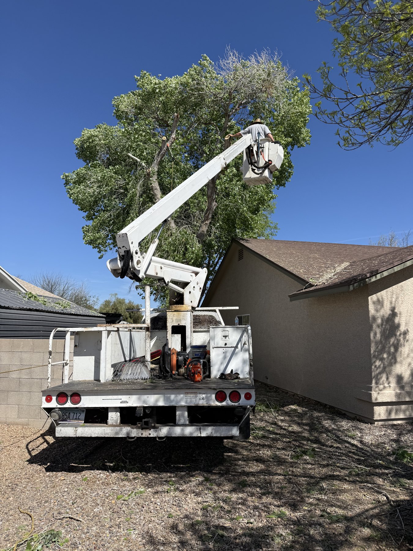 Bucket truck positioned beside a home for hazard tree removal